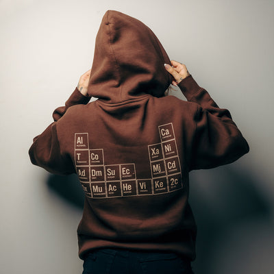 Official 27 Club Coffee Merchandise. Medium weight 100% cotton, brown unisex pullover hoodie featuring the 27 Club Coffee logo printed on the front left chest and the iconic periodic table art printed on the back.