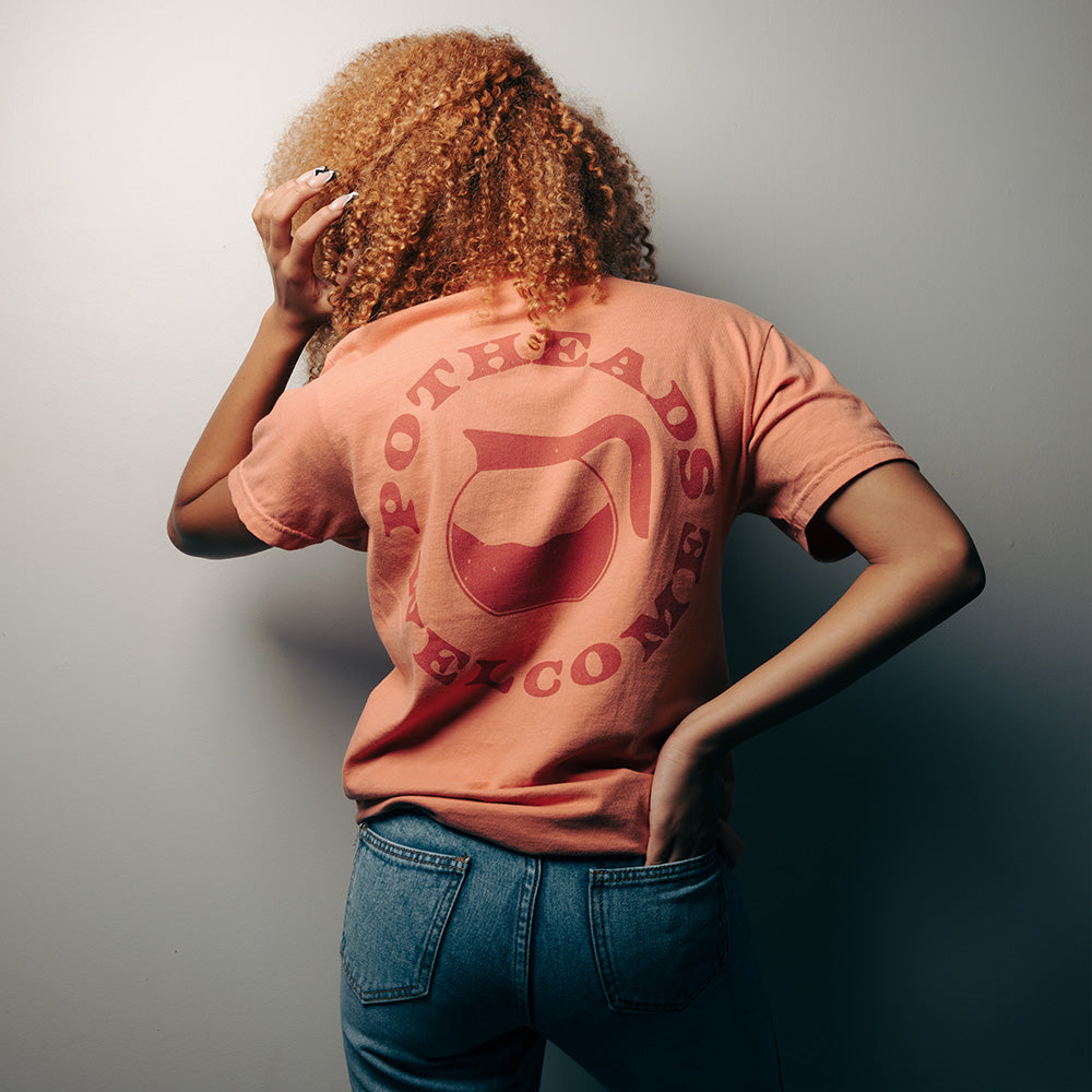 Official 27 Club Merchandise. Premium 100% cotton, unisex terracotta t-shirt with a relaxed fit featuring the 27 Club Coffee logo printed on the front left chest and the iconic Potheads Welcome logo printed across the back.